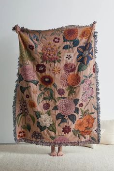 a woman standing in front of a blanket with flowers on it and fringes around the edges