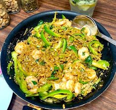 a pan filled with stir fry vegetables on top of a wooden table next to silverware