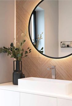 a bathroom sink with a mirror above it and a vase on the counter next to it