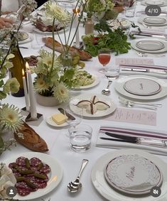 a long table is set with plates, silverware and flowers in white vases