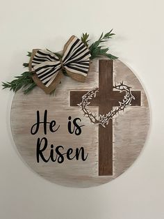 a wooden plaque with a cross and a bow on it that says he is risen