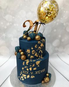 a blue cake with gold decorations and a large balloon on top that says love xxxv