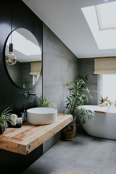 a bathroom with a large round mirror above the bathtub, and a plant on the counter