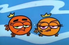 two oranges with crowns on their heads sitting next to each other in front of a blue sky