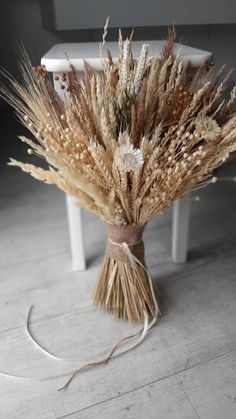 a bunch of dried plants sitting on top of a wooden floor next to a white table