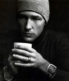 a black and white photo of a man holding a cup