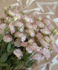 a bouquet of pink and white flowers sitting on top of a bed