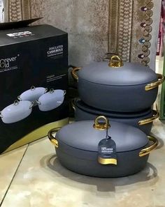 three pots and pans are sitting on the floor next to a box for glasses