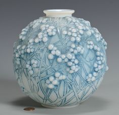 a blue and white vase sitting on top of a table next to a pile of coins