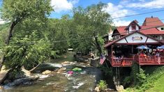 a river runs through the center of a town with people sitting at tables and umbrellas