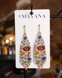 a pair of beaded earrings hanging from a hook on a display rack in a store