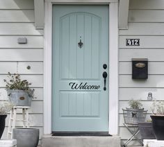 a blue front door with two planters on the steps next to it and a mailbox