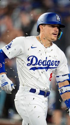 the dodgers baseball player is running with his bat in hand and confetti all around him