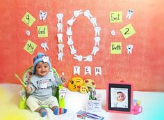 a baby sitting in a green chair next to a wall with letters and pictures on it