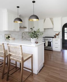 a kitchen with white cabinets and wooden flooring next to an island in the middle