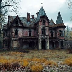 an old abandoned house in the middle of a field with grass and trees around it