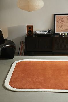 an orange rug in the middle of a room next to a record player and chair