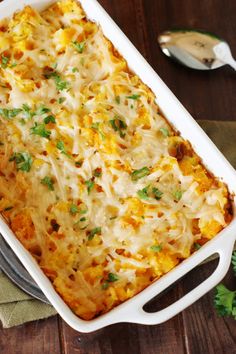 a casserole dish with cheese and parsley in it on a wooden table