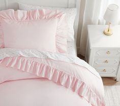 a bed with pink sheets and white pillows