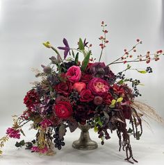 a vase filled with lots of different types of flowers and greenery on top of a table