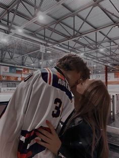 a man and woman kissing in front of an ice hockey goalie's jersey