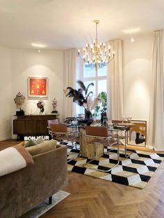 a living room filled with furniture and a chandelier hanging from the ceiling over a checkered area rug