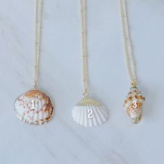 Dive into the deep blue of summer fashion with these gorgeous gold seashell necklaces! Walk the beach in style with perfect accessories that blend the beauty of the sea with the luxury of shimmering gold. Wave goodbye to basic jewelry and make a statement with these stunning necklaces! Gold-detailed seashell charms on a 14k gold plated satellite chain. Necklaces are 16 inches in length and include a 2-inch extender. Elegant Beach Pendant Charm Necklaces, Elegant Pendant Charm Necklaces For The Beach, Elegant Beach Pendant Charm Necklace, Dainty Shell Charm Necklace For Beach, Elegant Shell-shaped Charm Necklaces For Beach, Ocean-inspired Shell-shaped Necklaces With Lobster Clasp, Gold Coastal Necklace For Vacation, Coastal Style Gold Necklace For Vacation, Dainty Shell Jewelry For Beach