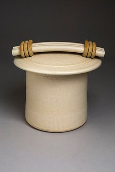 a white hat with two wooden handles on it's top and the handle is made out of wood