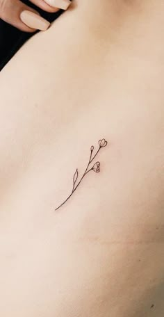 a woman's stomach with a small flower tattoo on her left side ribcage