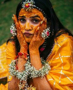 a woman with her hands on her face covered in yellow and white flowers, posing for the camera