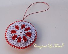 a red and white ornament hanging from a string on top of a table