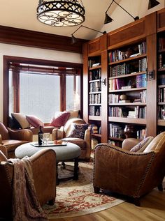 a living room filled with lots of furniture and bookshelves next to a window