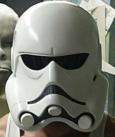 a man wearing a star wars helmet next to a white mask on his face and nose