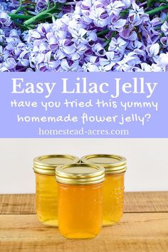 three jars filled with honey sitting on top of a wooden table next to purple flowers