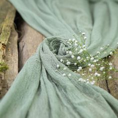 a green scarf with white flowers on it sitting on top of a piece of wood