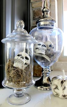 two glass jars filled with skulls sitting on top of a counter