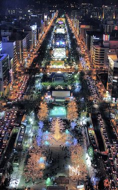 an aerial view of a city at night with lots of lights on the buildings and streets