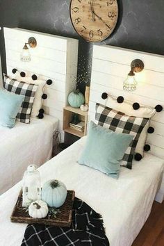 two twin beds in a room with black and white decor on the walls, one has a clock above them