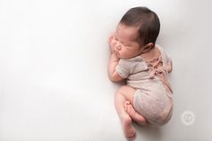 a baby sleeping on top of a white blanket with its eyes closed and hands behind her head