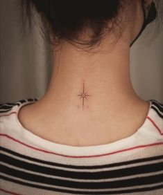 a woman's neck with a small cross tattoo on the back of her neck