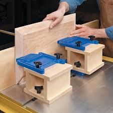 two people are working on woodworking with blue plastic containers in front of the workbench