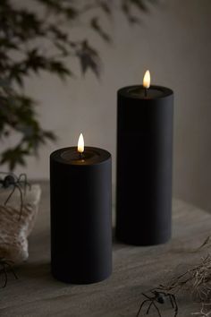 two black candles sitting on top of a table