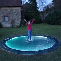 a person jumping in the air on top of a trampoline with their arms up