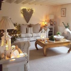 a living room filled with white furniture and christmas lights on the wall next to a fire place