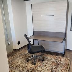 an office area with a rug, chair and desk in the middle of the room