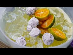 a bowl filled with oranges and ice on top of a table