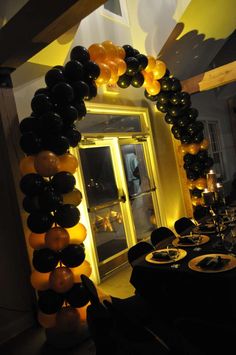 an arch made out of balloons in the shape of pumpkins and black, yellow and white balloons