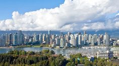 the city is surrounded by tall buildings and trees in front of a large body of water