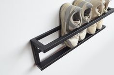 there are four pairs of shoes hanging on the wall with one shoe rack in front of them