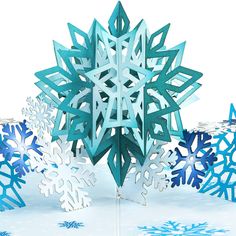 a snowflake made out of blue and white paper on top of snow covered ground